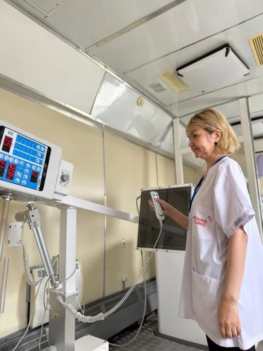 В центре — современный медицинский поезд с надписью «Саламатты Қазақстан». Рядом — местные жители, включая детей и пожилых, ожидают осмотра. Врачи в белых халатах встречают людей у входа.