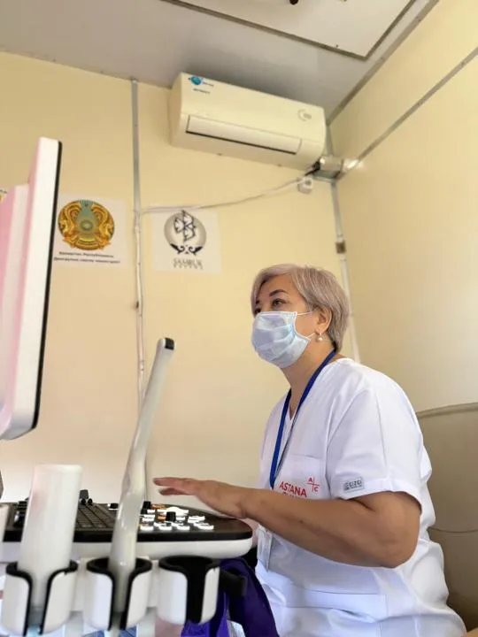 В центре — современный медицинский поезд с надписью «Саламатты Қазақстан». Рядом — местные жители, включая детей и пожилых, ожидают осмотра. Врачи в белых халатах встречают людей у входа.