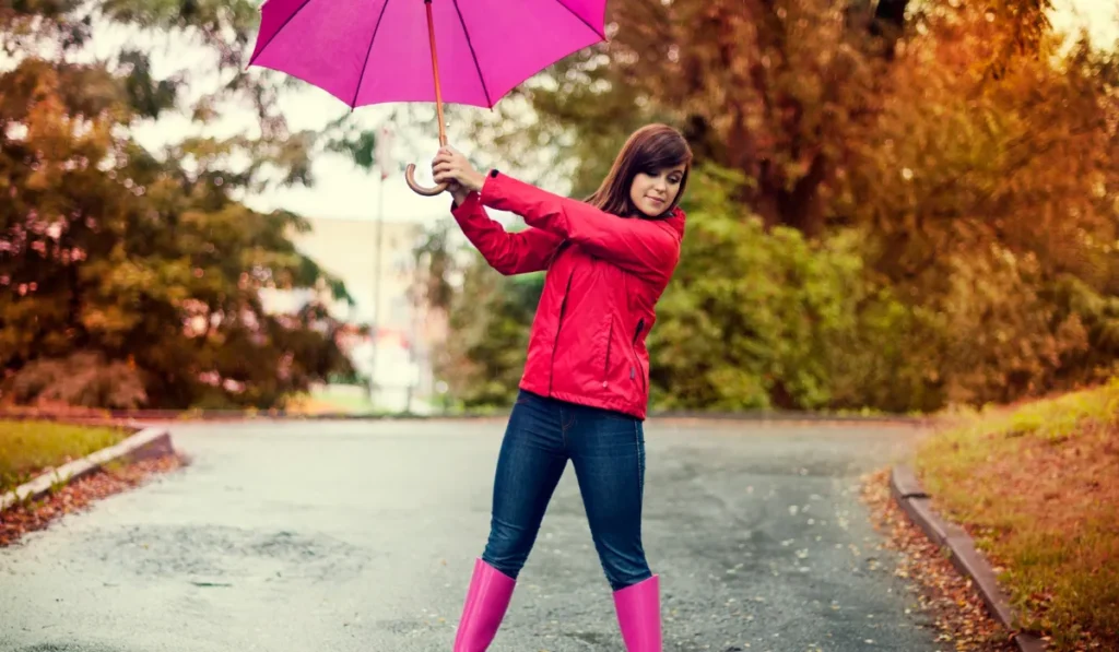 Девушка в красном держит зонт в руках в дождливую погоду